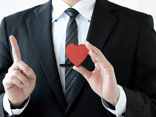 スーツの人物がハートの模型を持っている様子