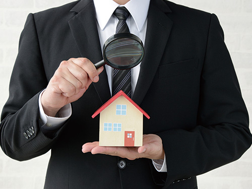 スーツの人物が家の模型を持っている様子